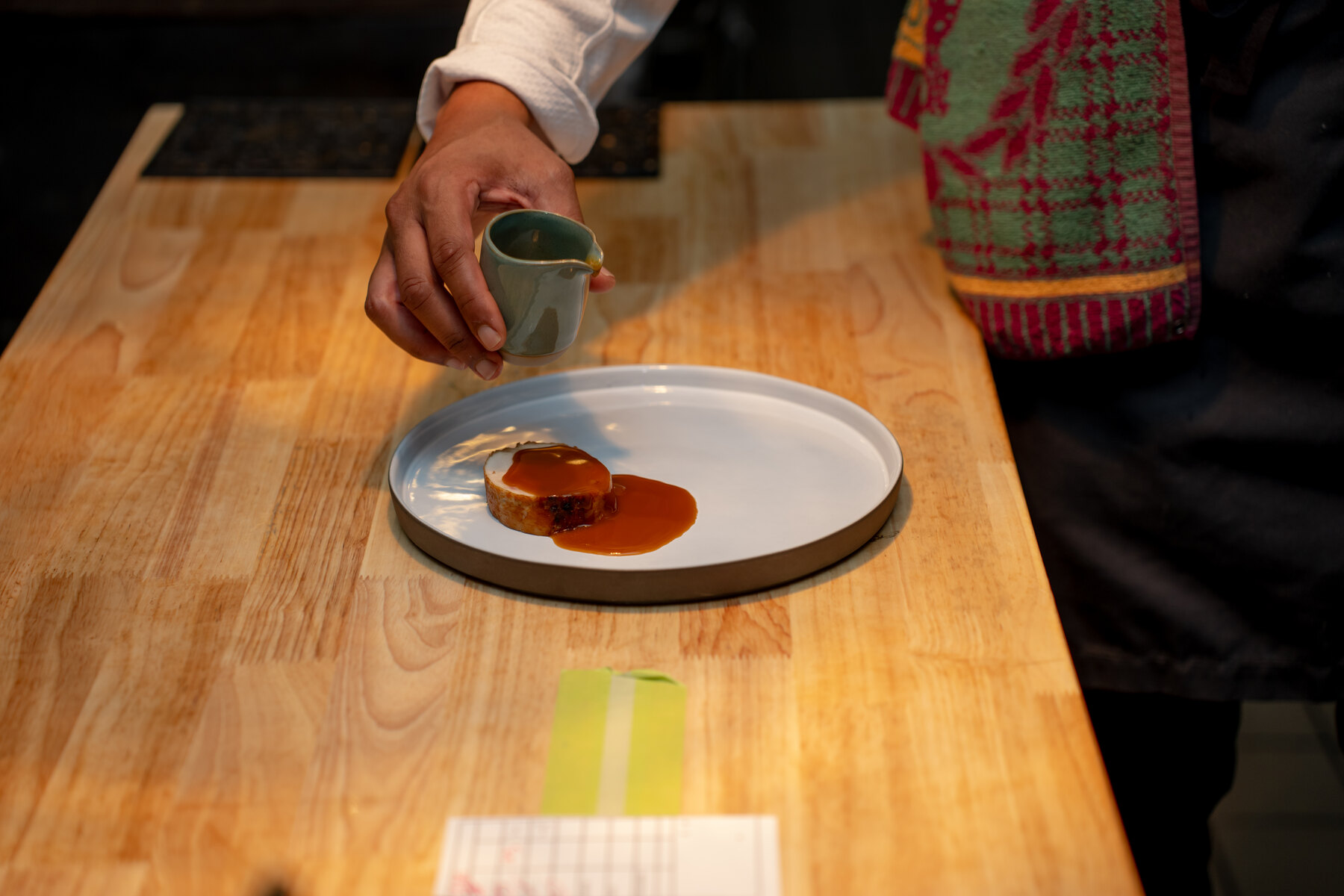 Sauce being poured onto a plated Harrisburg course