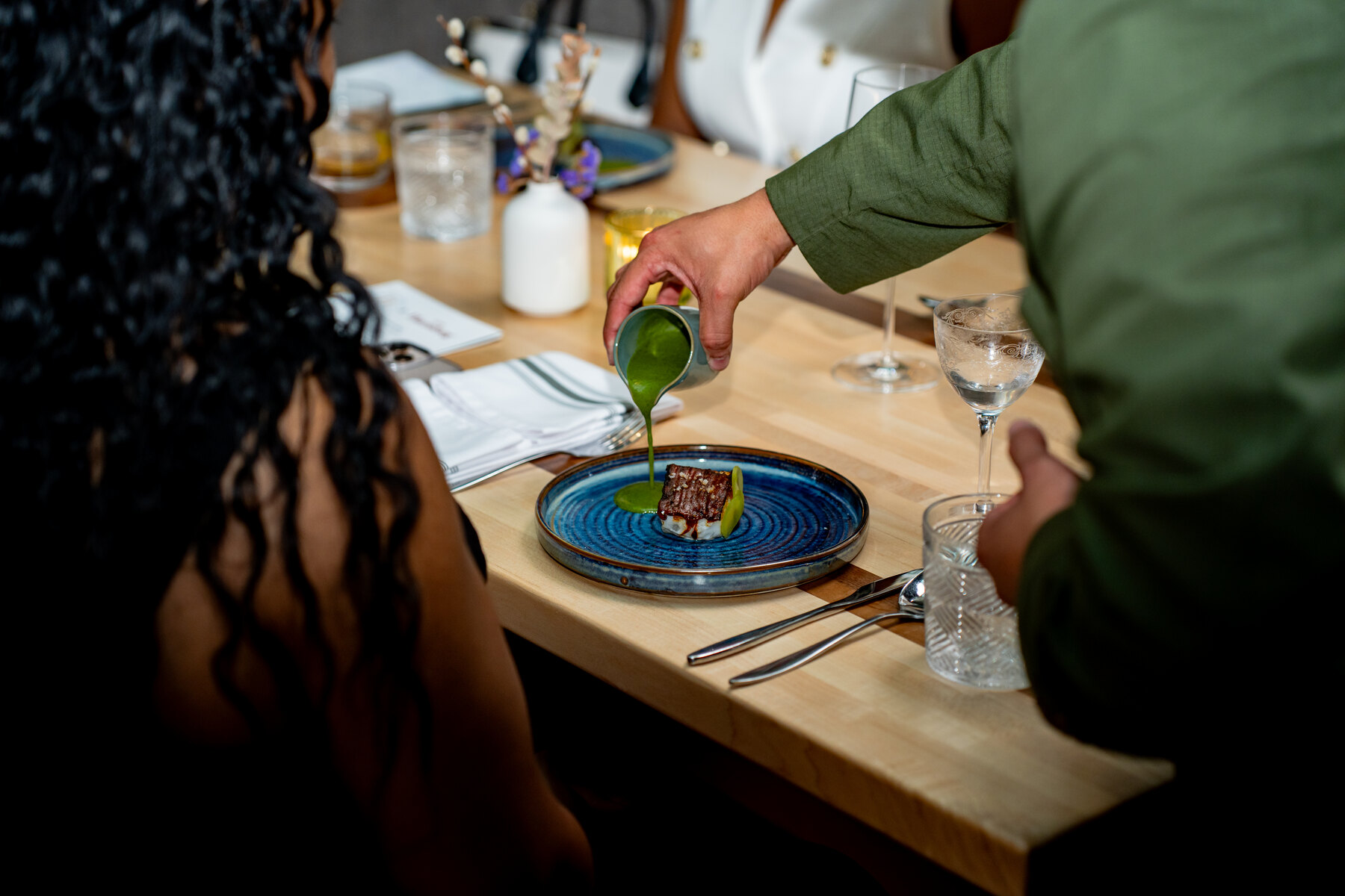 A green sauce poured tableside over a plated course