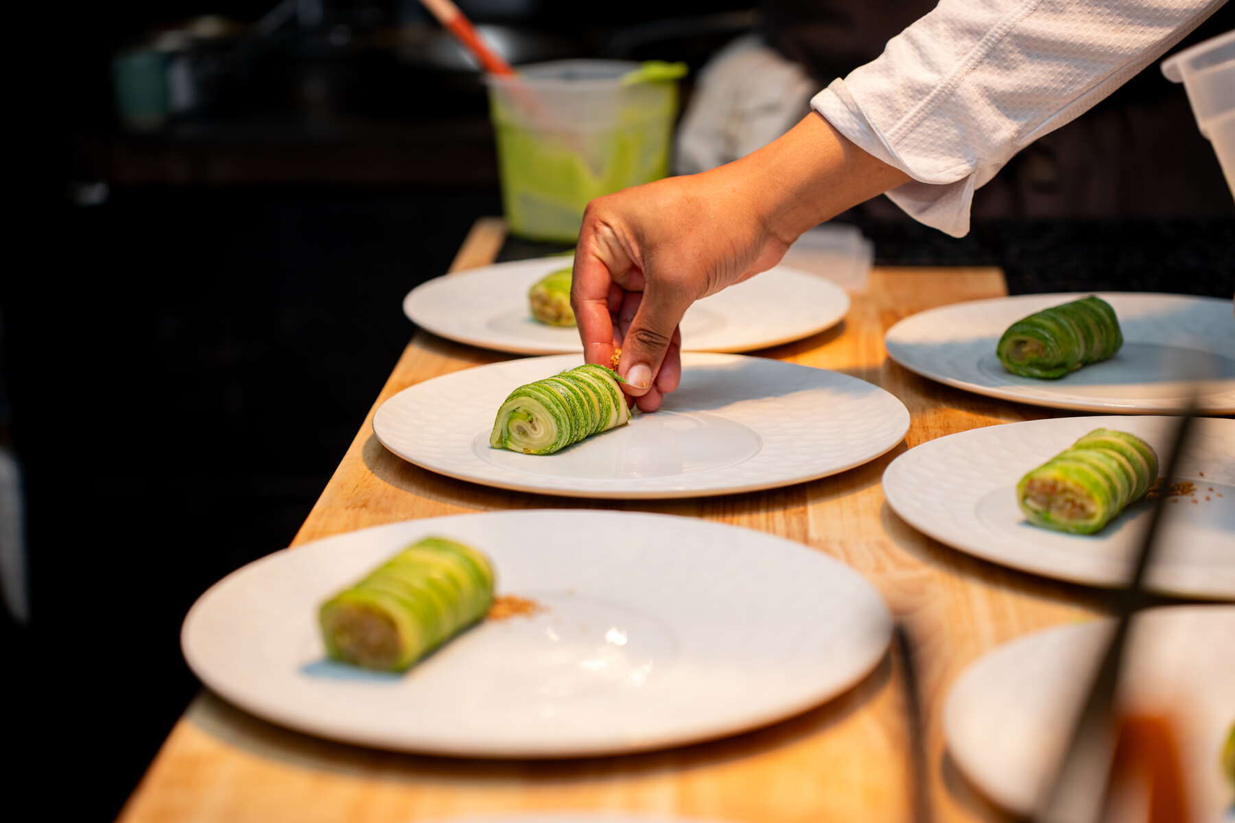 Chef plating rolled green courses on white plates
