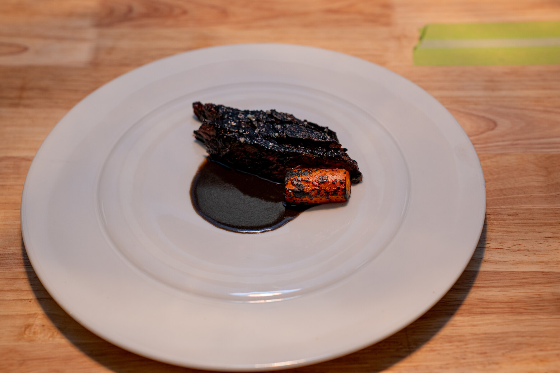 Charred Harrisburg course with dark sauce on a white plate