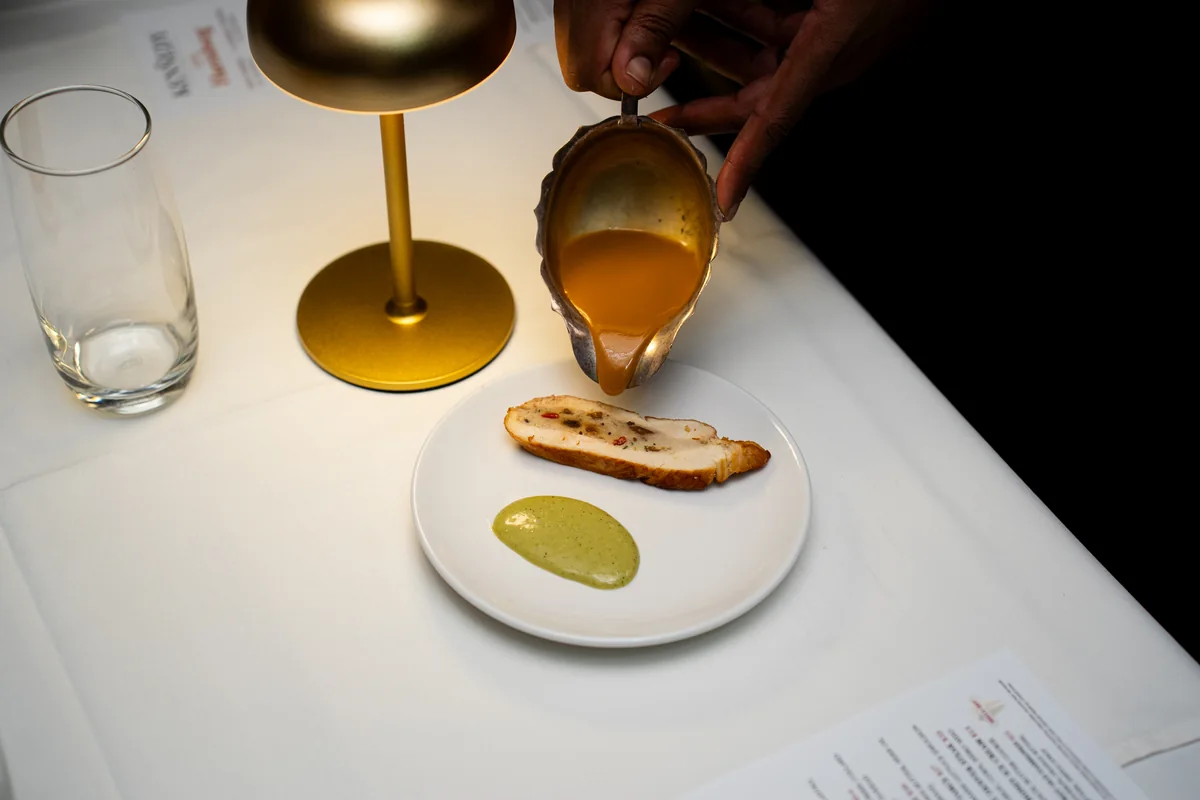 Sauce poured tableside over a plated course beside a gold lamp at The Kennedy